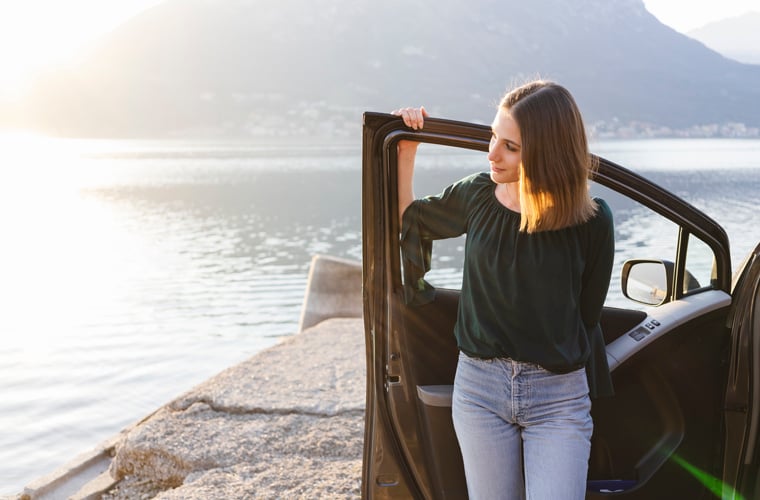 girl standing alone next to car looking off into distance iStock-1137426845 760x500